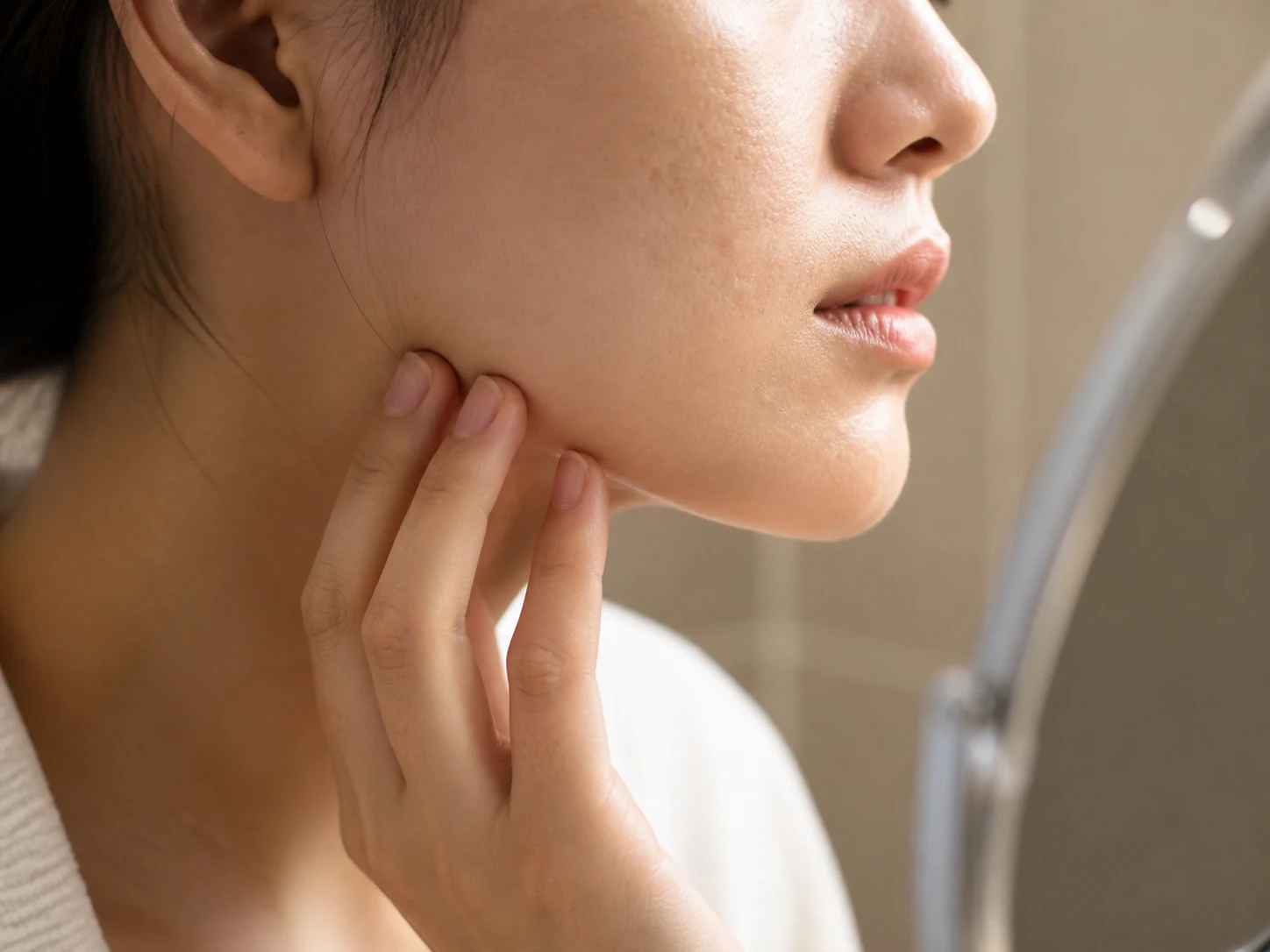 여드름 흉터 종류를 확인하기 위해 측면 조명 아래 볼의 패인 자국을 살펴보는 장면